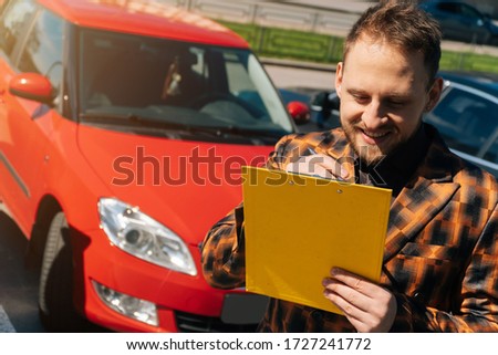 A young joyful man fills out documents about the sale of his car. concept of changing transport. 