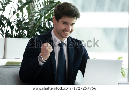Businessman in formal elegant suit sitting at office desk read news on pc feels excited by fantastic new business opportunity. Receive promotion email, celebrating triumph success at workplace concept Royalty-Free Stock Photo #1727257966