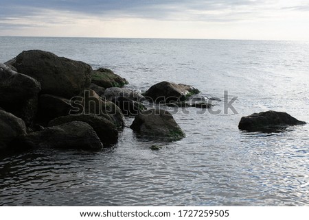 Sea but against the background of clear sky and waves. Sunset on the background of the sea. Postcard or wallpaper on the wall. Rocky shore.