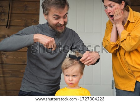 Family haircut at home during quarantine when closed all hairdressers. Father cut hair for son and mother is shocked by it. Focus on mom. Beauty and selfcare at home, crazy lifestyle during lockdown. Royalty-Free Stock Photo #1727304223