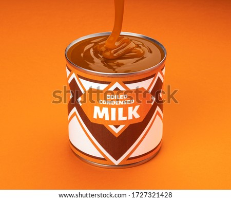 Flowing melted boiled condensed milk into can isolated on orange color background