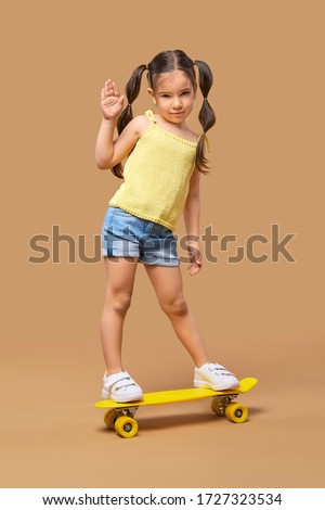 Active young girl on skateboard showing hello sign