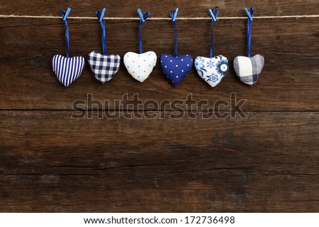 Blue Gingham Love Valentine's hearts natural cord and blue clips hanging on rustic driftwood texture background, copy space
