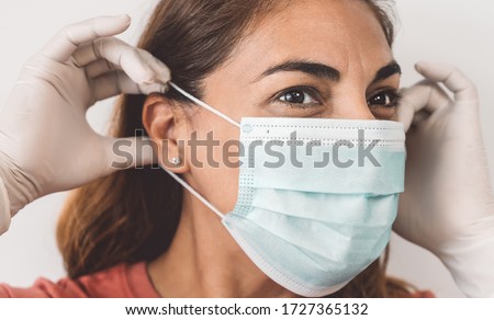 Mature Latin woman portrait wearing surgical face mask and gloves - People self quarantine for preventing and stop corona virus spread - Healthcare and coronavirus confinement concept Royalty-Free Stock Photo #1727365132