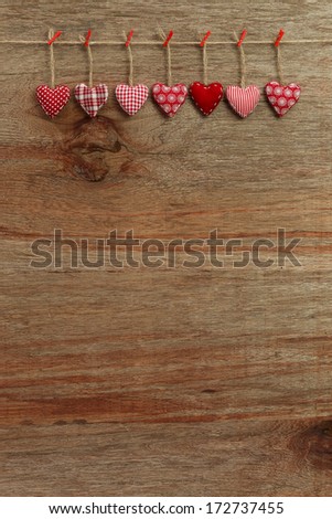 Gingham Love Valentine's hearts natural cord and red clips hanging on rustic plywood texture background, copy space
