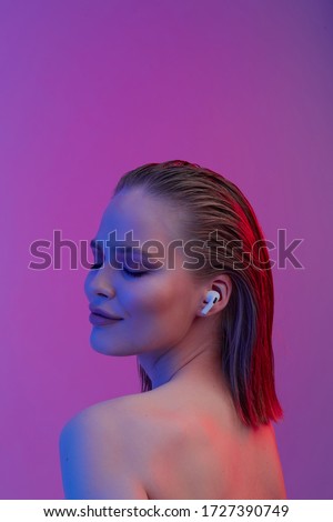 A beautiful young girl in wireless headphones listens to song with a good mood. bright colorful music poster. Royalty-Free Stock Photo #1727390749