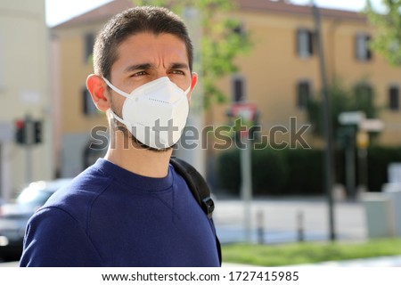 COVID-19 Pandemic Coronavirus Man in city street wearing KN95 FFP2 face mask protective for spreading of Coronavirus Disease 2019. Portrait of man with face mask against SARS-CoV-2. Royalty-Free Stock Photo #1727415985