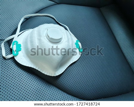 Aseptic ffp3 / N95 face mask with black valve placed on the car seat These devices are important to today's society with air pollution and the spread of coronavirus (COVID-19).