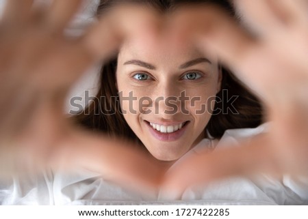 Woman in love wakeup lies in bed look at camera showing with hands heart shape close up view from above focus on happy face, mattress pillow high quality bedclothes, good morning enjoy new day concept Royalty-Free Stock Photo #1727422285
