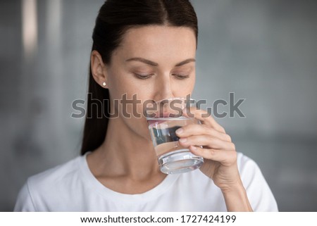 Woman drinks still water close up portrait. Quench thirst, water balance and weight control, caring of skin and body, hangover relief, body refreshment, energy recovery, dehydration prevention concept Royalty-Free Stock Photo #1727424199