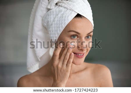 Close up face reflected in mirror of beautiful 35s woman applying cream self-care grooming activity after shower indoor. Wrinkles prevention antiaging beauty treatment for healthy radiant skin concept Royalty-Free Stock Photo #1727424223