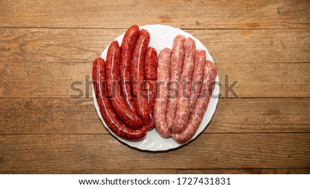 
Sausages and merguez arranged in a white plate, on a woody background Royalty-Free Stock Photo #1727431831