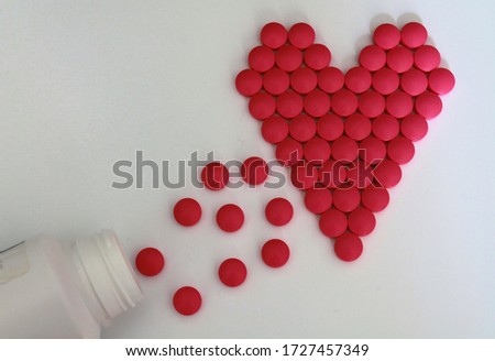 Pills poured out from a bottle into a heart shape.