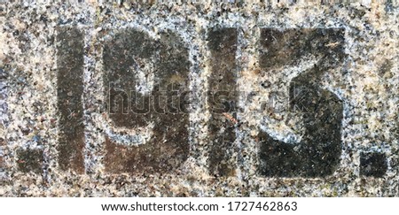 "1913" chiselled out of granite and polished – a detail of an inscription produced that year. Partly covered with dirt