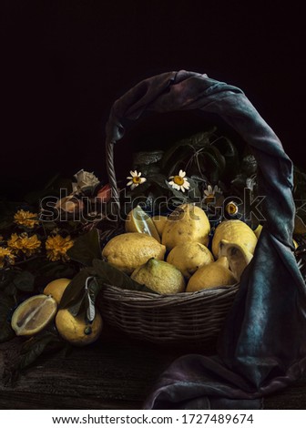 Lemon in basket and flower and green leaf in dark background.