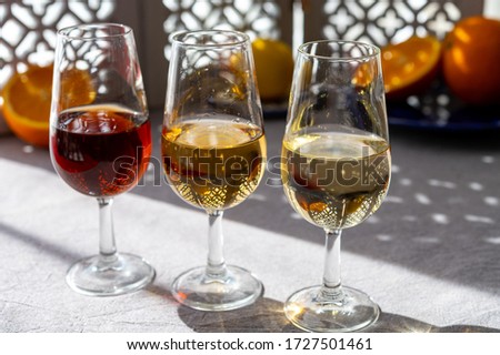 Glasses with cold dry fino and sweet cream sherry fortified wine and orange in summer sunlights, andalusian style interior on background