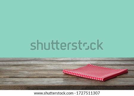 Folded kitchen towel on wooden table against mint background. Space for design