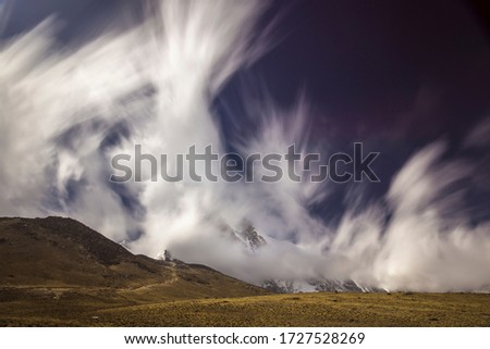 Long exposure picture of fast-moving clouds and blue sky over Himalayan mountains