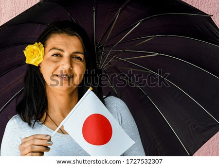 Woman with umbrella holds flag of Japan
