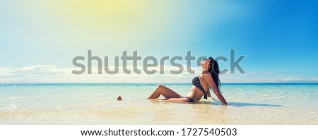 Girl in black swimwear tan on  beautiful beach. Tropical vacation concept. Banner edition.