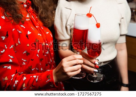 Holiday concept, hands of young girls holding glasses with drinks, clinking glasses