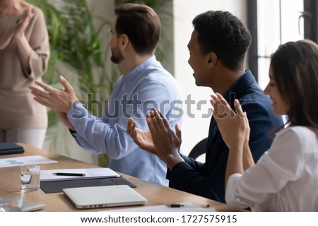Close up smiling african american businessman clap hands with diverse colleagues congratulating after flip charts presentation in boardroom at meeting. Smiling employee happy about successful project. Royalty-Free Stock Photo #1727575915