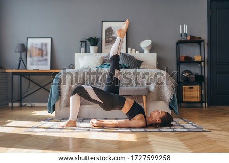 Fit woman trains at home and does exercise glute bridge. Royalty-Free Stock Photo #1727599258