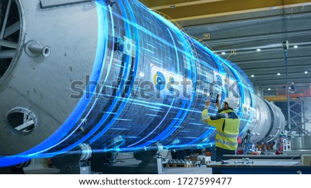 AR Concept: Industrial Engineer Uses Augmented Reality Digital Tablet to Scan Large Metal Construction, Special Effects Show Visualization / Digitalization of Oil, Gas and Fuel Transport Pipeline. Royalty-Free Stock Photo #1727599477