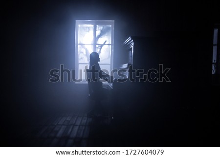 A realistic dollhouse living room with furniture and window at night. Woman sitting at the old piano in dark room. Selective focus.