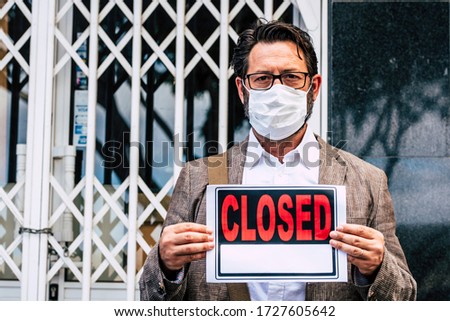 Adult professional businessman with closed sign outside his store for coronavirus economy crisis emergency for lockdown at home - business recession concept with owner outdoor shop