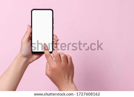 Concept of use of the smartphone. A smartphone with a white blank screen in the hands of a woman. On a pink background.