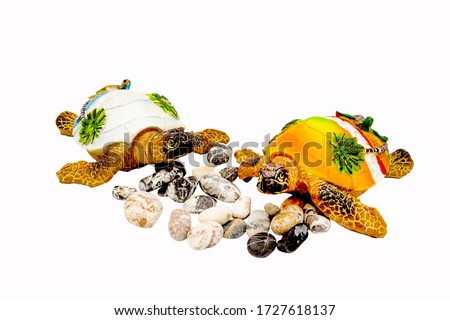 Two isolated souvenir turtles opposite each other on a white background. Side view. Between the turtles are colored stones and pebbles.