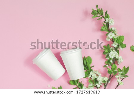 paper cup with coffee and blossom on the pink background