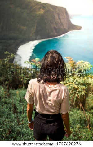 Girl on cliff facing the ocean