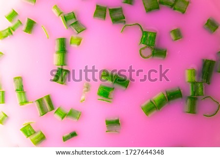 Abstract contemporary background. Photograph of green chopped onions inside a purple liquid.
