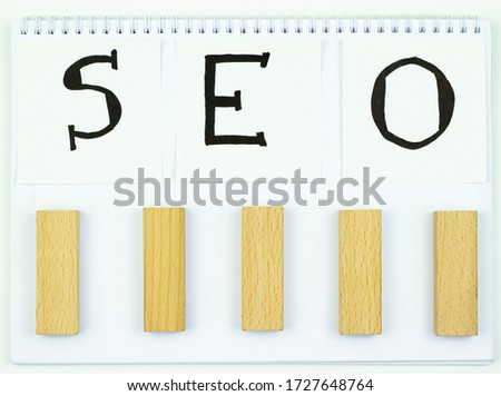 SEO inscription with black marker on white paper with wooden blocks. Search engine optimization concept.