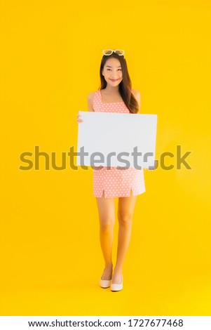 Portrait beautiful young asian woman show empty white billboard for text and copyspace on yellow isolated background