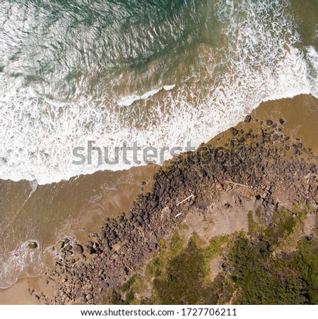 Waves on the shore of the Pacific Ocean, cliffs beach and water, top view. Texture and landscape.