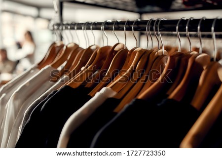 Close up of clothes rack or rail in the store. Items at custom T-shirt, clothing printing company. Horizontal shot Royalty-Free Stock Photo #1727723350