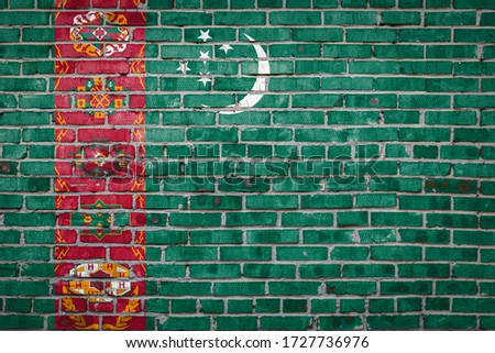 National flag of Turkmenistan  depicting in paint colors on an old brick wall. Flag  banner on brick wall background.