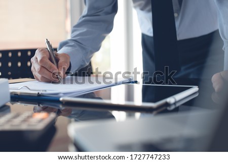 Businessman reading document before signing business contract or partnership agreement with digital tablet on desk. Corporate man, accountant working in modern office.