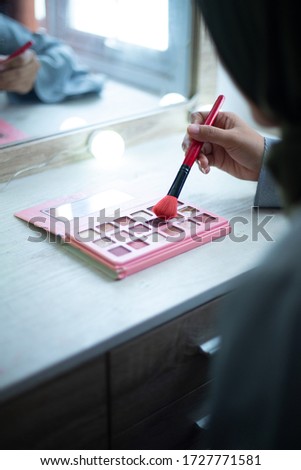 Closeup woman hand while holding the brush and polishing the powder pallet in makeup room