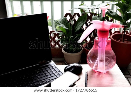 Stay at home, Work form home concept. Laptop computer on the table with Water Spray Bottle. tree background.