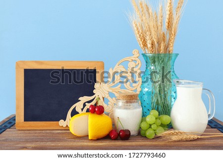photo of dairy products over old wooden table and pastel background. Symbols of jewish holiday - Shavuot