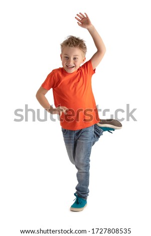 LITTLE BOY SMILING HAPPY WHILE BALANCING ON ONE LEG WITH ONE HAND UP ISOLATED ON WHITE BACKGROUND, HAPPY ACTIVE KID