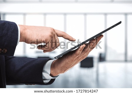 Man using digital tablet in bright sunny office, close up. Technology concept