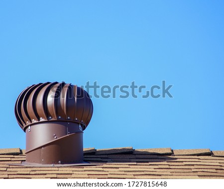 A brown internally braced wind turbine on top of a shingles roof.