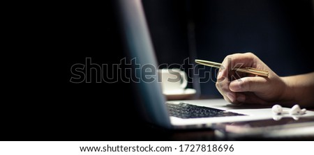 man using laptop or computer working at home in the at night and have glass coffee, book on table. for web banner with copy space. 
