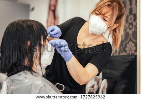 Cutting the bangs to a client with security measures. Reopening with security measures of Hairdressers in the Covid-19 pandemic Royalty-Free Stock Photo #1727825962