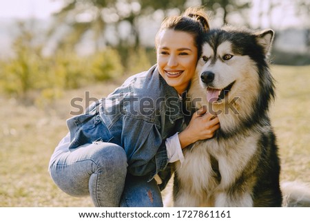 Woman in a spring forest. Girl with cute dog. Brunette in a jeans jacket.